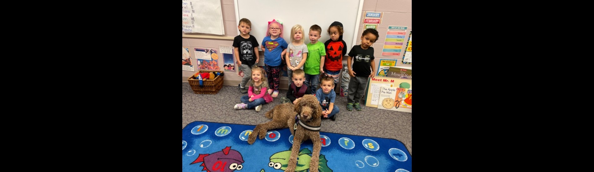 Preschool students strike a pose with the school therapy dog.